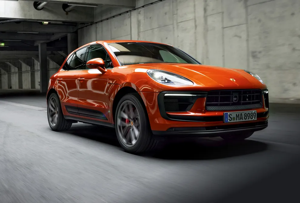 Un Porsche Macan S en color Papaya Metalizado circulando por un túnel. Vista frontal y lateral.