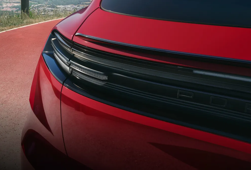 Side view of the rear end of a Porsche Macan GTS in Carmine Red with focus on the spoiler with GTS-specific spoiler lip and the light strip.