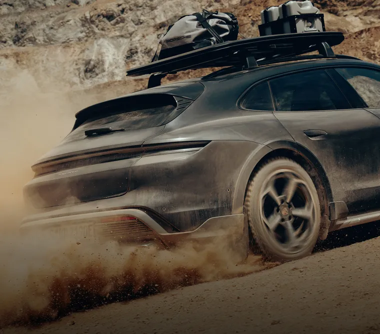 Ein Porsche Taycan Cross Turismo mit Adventure Zubehör und Offroad Design Paket fährt durchs Gelände.