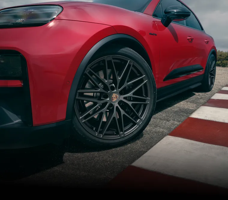 Widok Porsche Macan GTS w kolorze Carmine Red z boku, ze szczególnym uwzględnieniem przedniego koła.