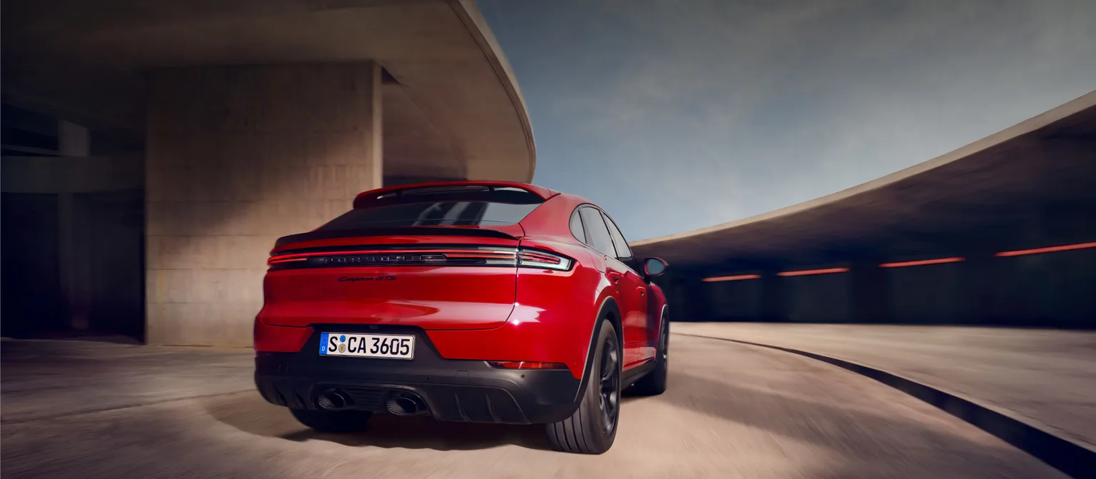 Blick von hinten auf das Heck eines fahrenden Porsche Cayenne GTS Coupé in Karminrot.