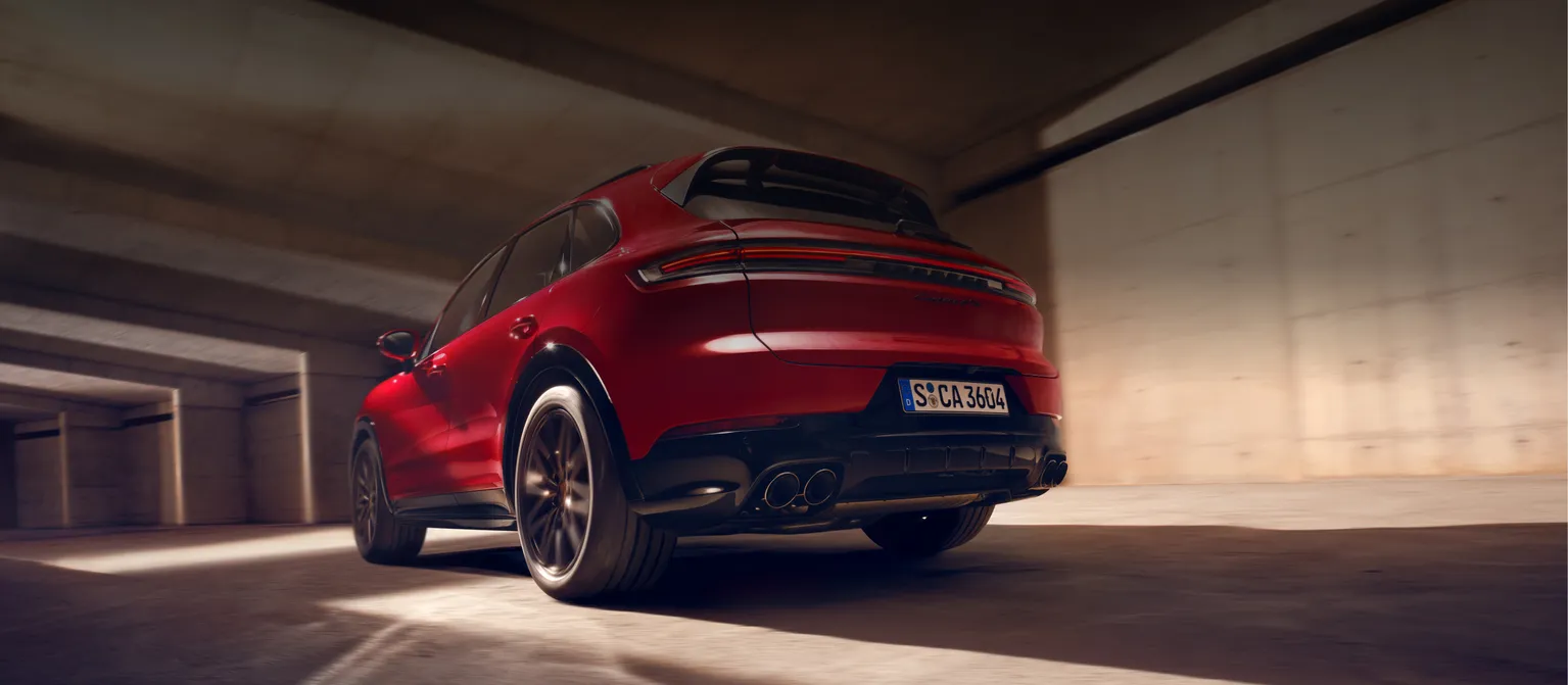 Вид сзади на заднюю часть движущегося Porsche Cayenne GTS цвета красный неметаллик (Carmine Red).