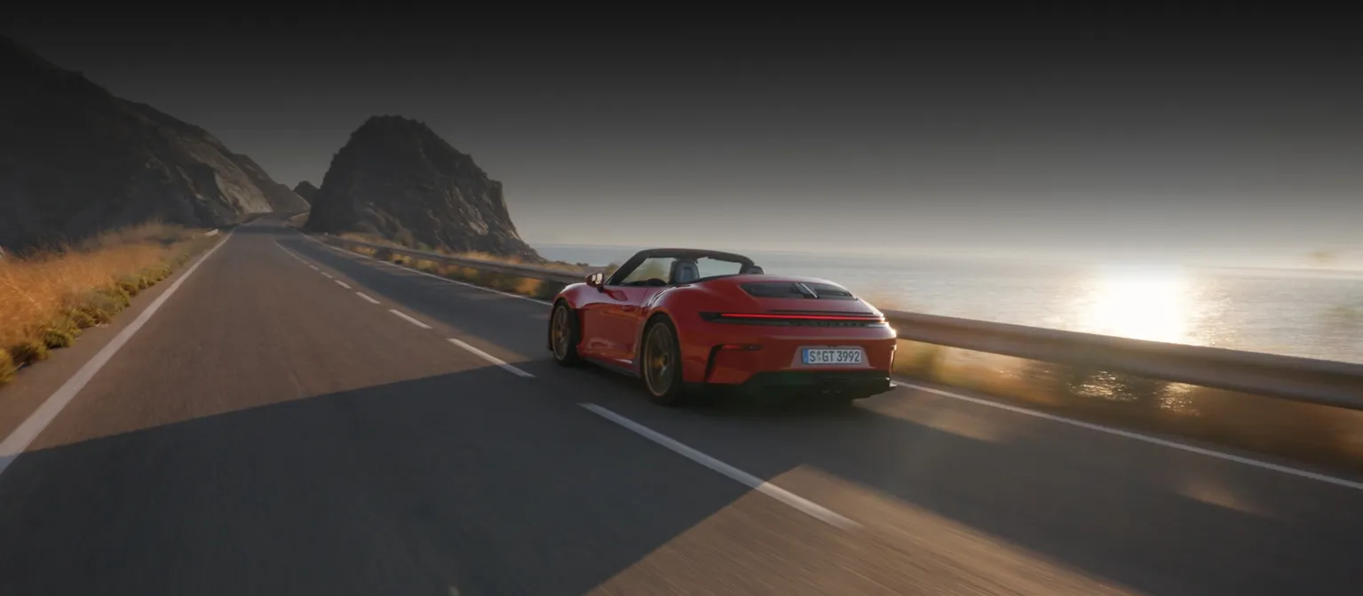Rear view of a Porsche 911 GT3 S/C in Guards Red driving on a country road.