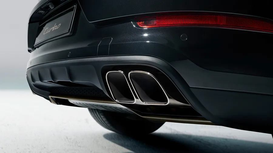 Detailweergave van het uitlaatsysteem met dubbele eindpijpen in donkerbrons bij de Porsche Cayenne Turbo E-Hybrid.