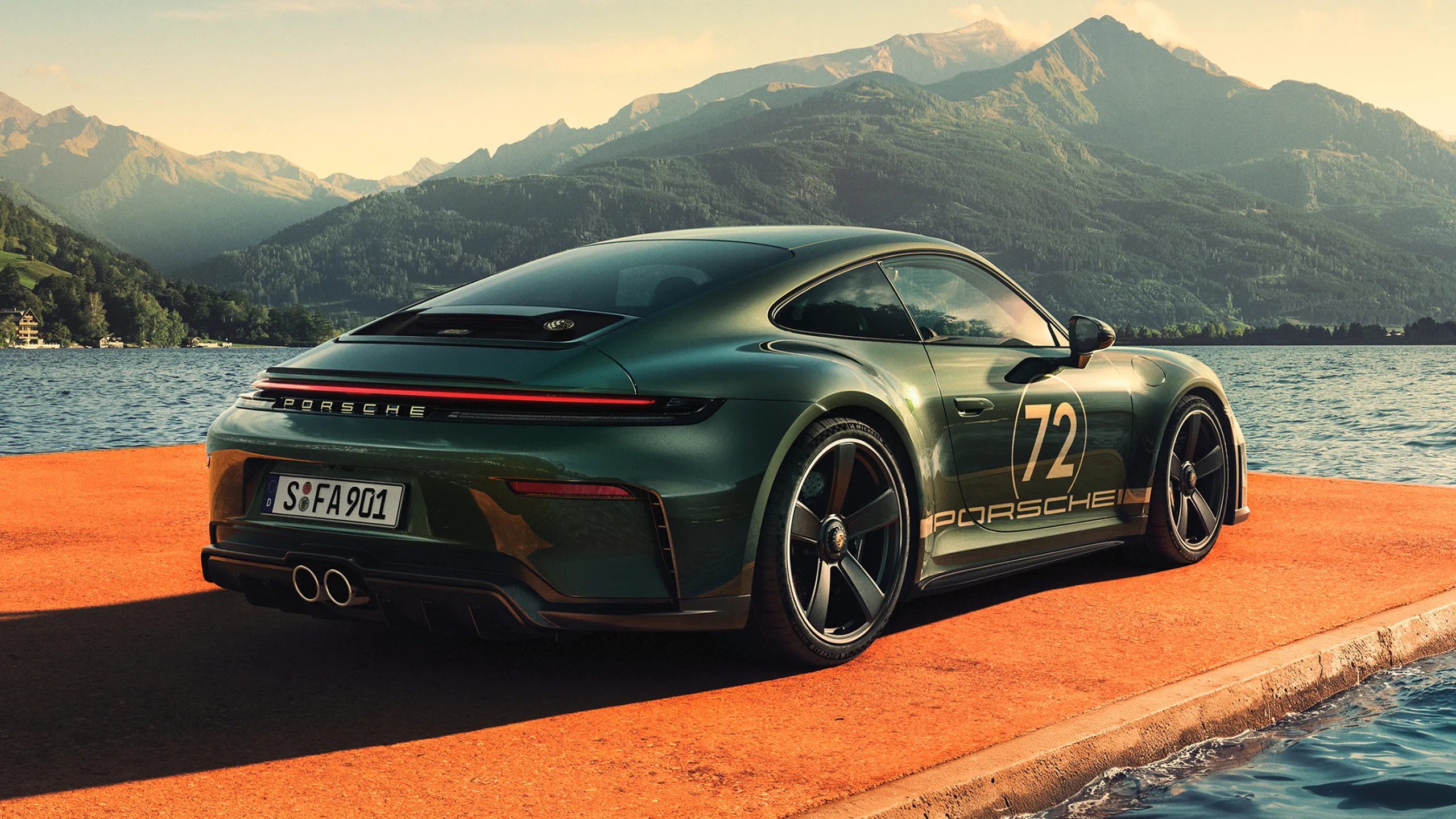 Rear end and side view of a Porsche 911 GT3 90 F. A. in F. A. Greenmetallic on a jetty. Mountains and a lake can be seen in the background.