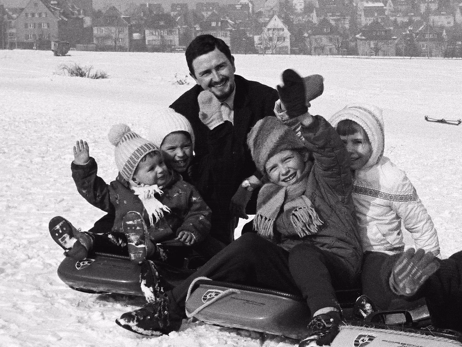Foto storica di F. A. Porsche con dei bambini su una slitta Porsche su un prato innevato.