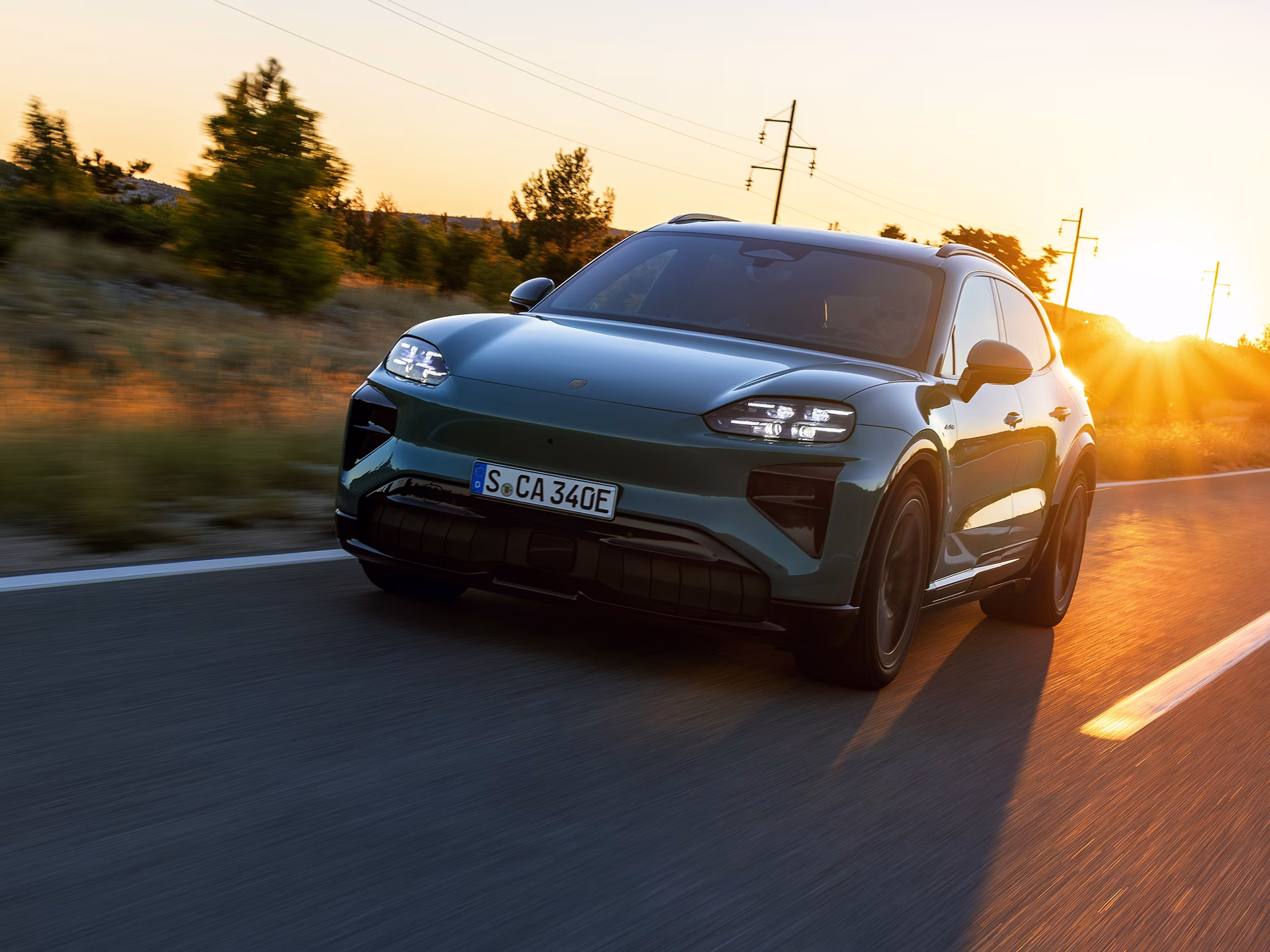 A Porsche Cayenne Turbo in Mystic Green Metallic driving on a country road.