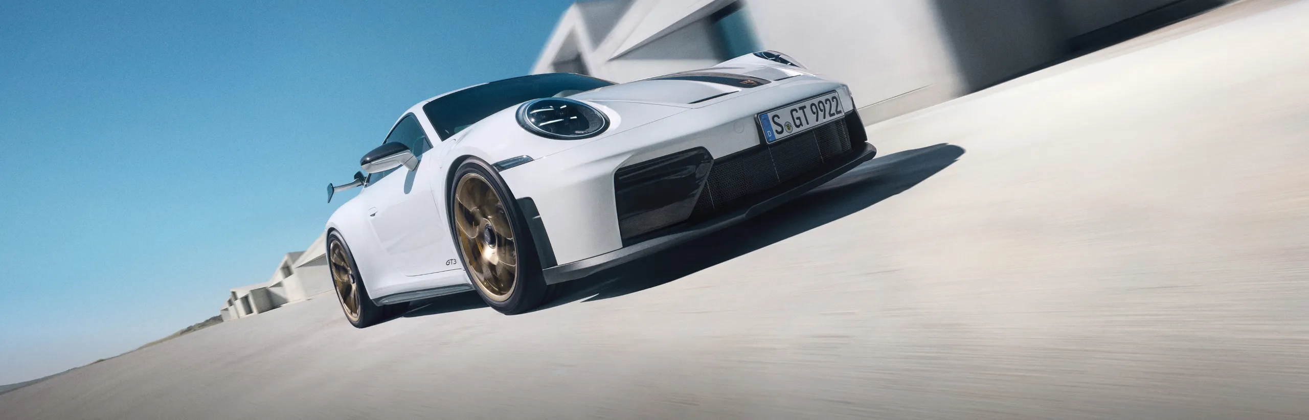 Blick auf Front und Seite eines fahrenden Porsche 911 GT3 in Weiß mit Weissach-Paket.