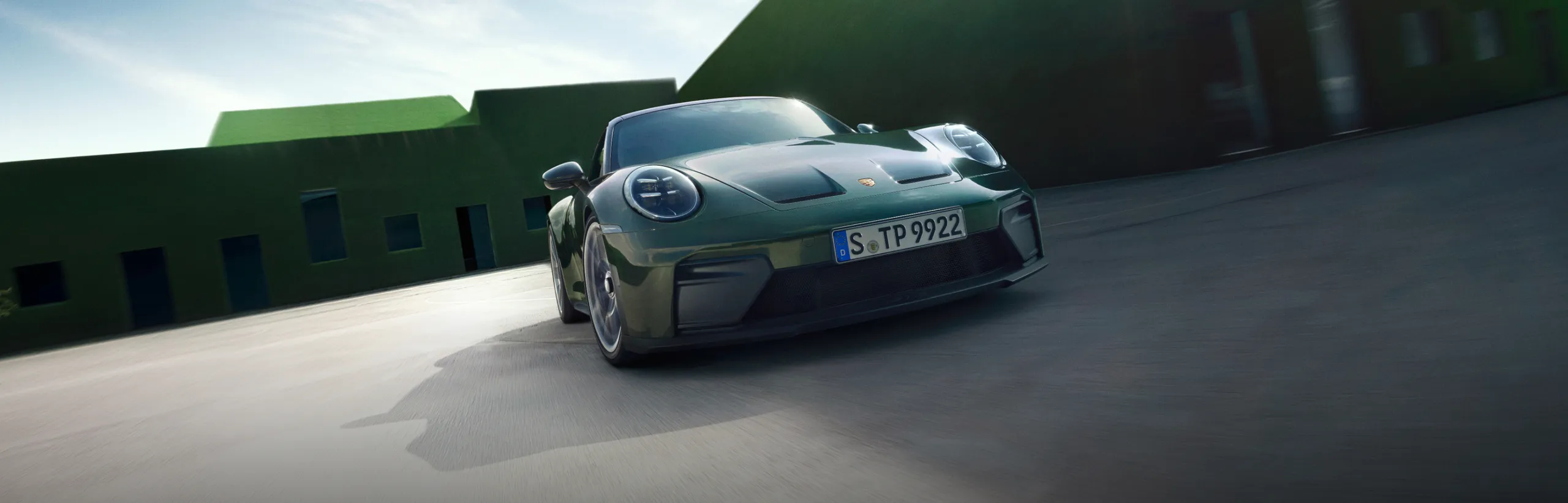 Vista dal davanti del frontale e della fiancata di una Porsche 911 GT3 con pacchetto Touring in Oak Green metallizzato neo.