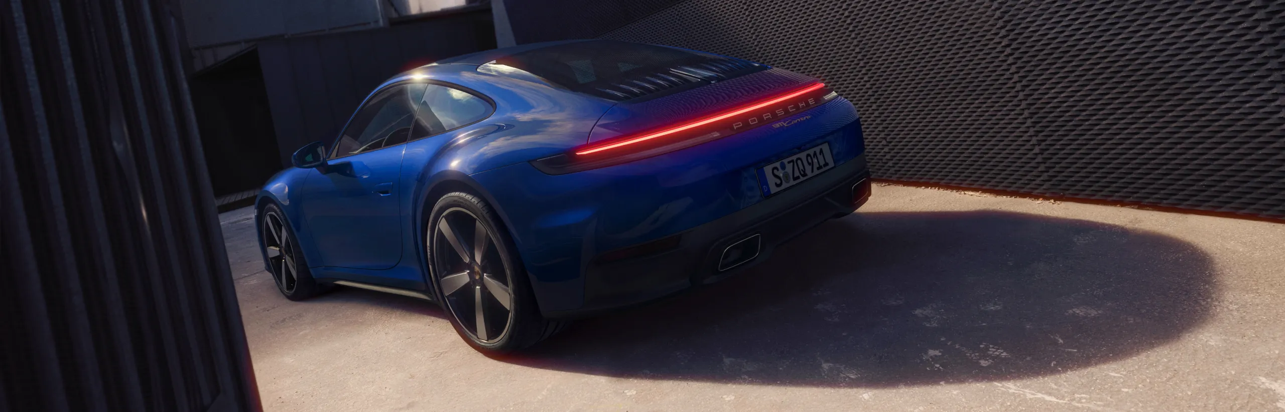 Un Porsche 911 Carrera GTS en color Gris Pizarra Neo circulando por una carretera. Vista desde delante de la parte delantera.