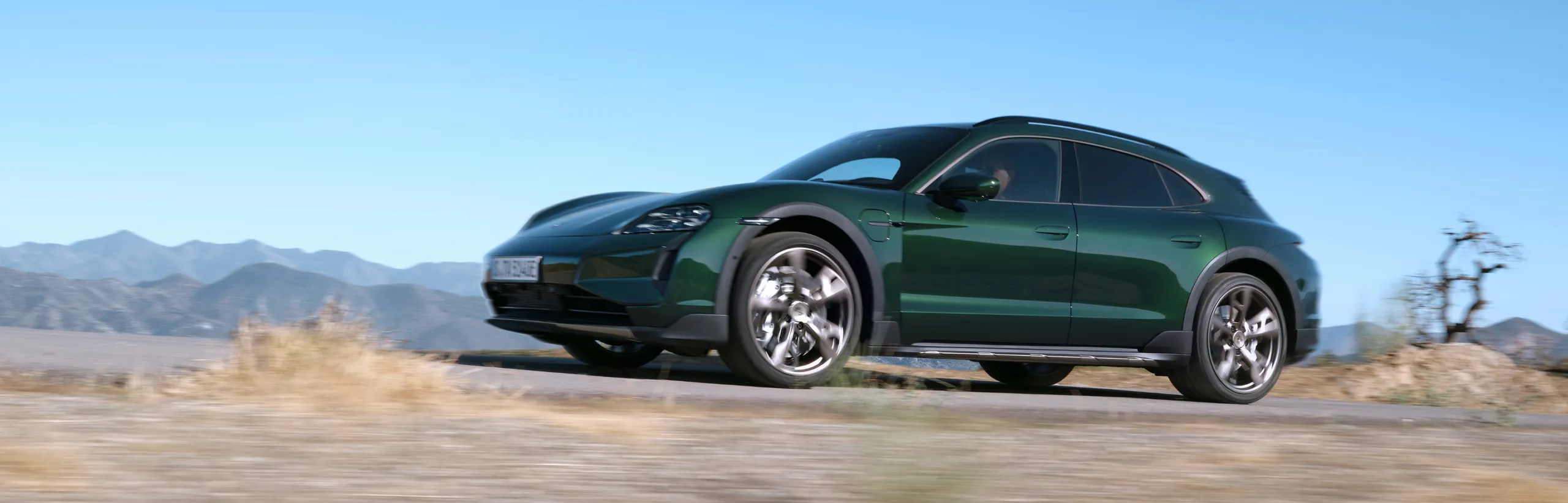 Porsche Taycan Turbo Cross Turismo in Oak Green Neo driving through the countryside. Side view.
