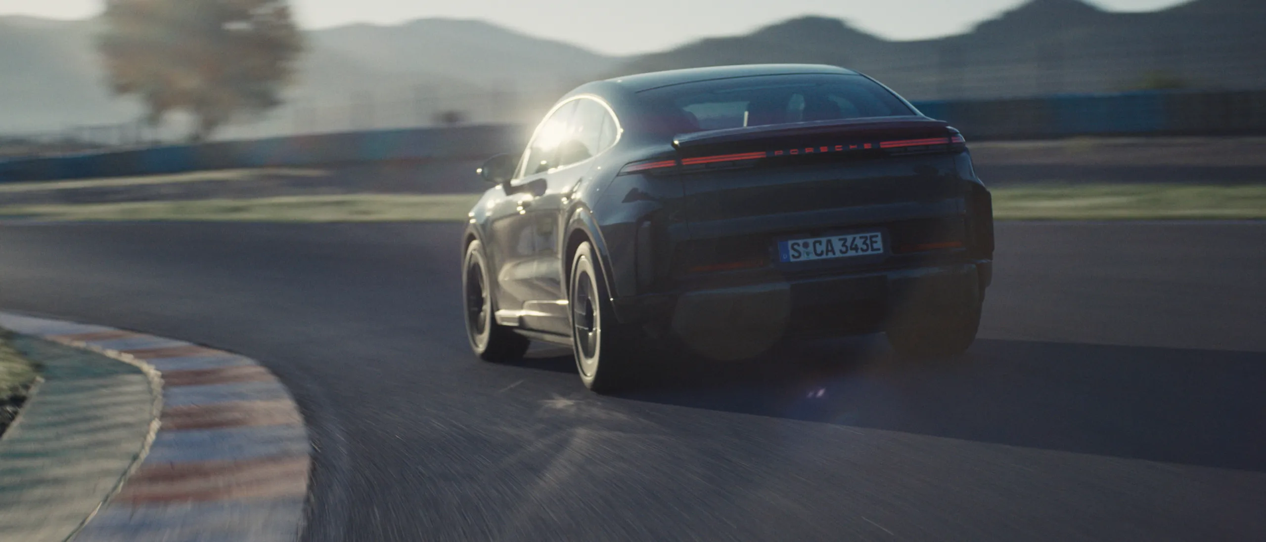 Ein Porsche Cayenne Turbo Coupé in Monteverdemetallic fährt auf Landstraße.