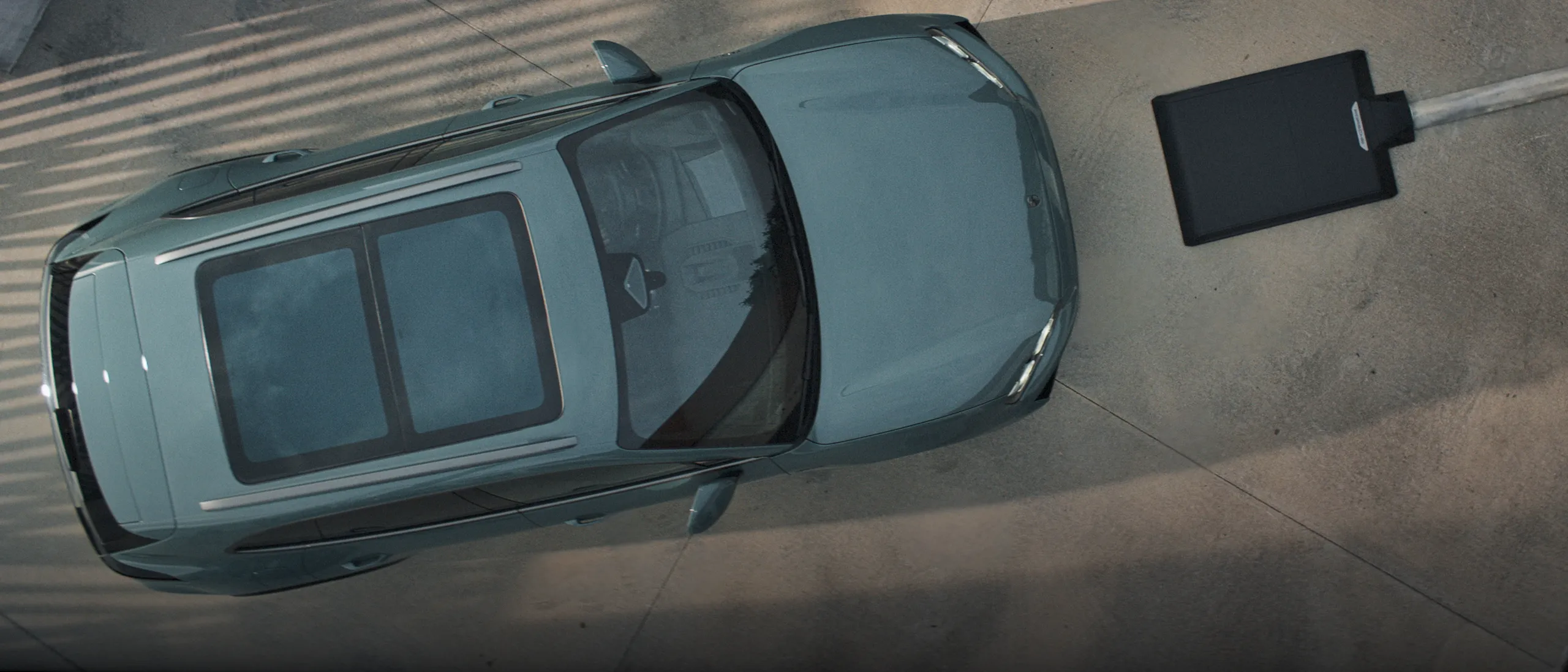 A Porsche Cayenne Turbo in Mystic Green Metallic charging at a charging pedestal.