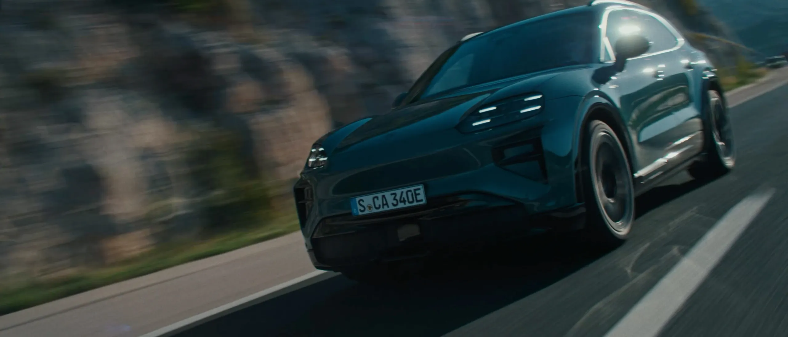 A Porsche Cayenne Turbo in Mystic Green Metallic driving on a country road. Front and side views.