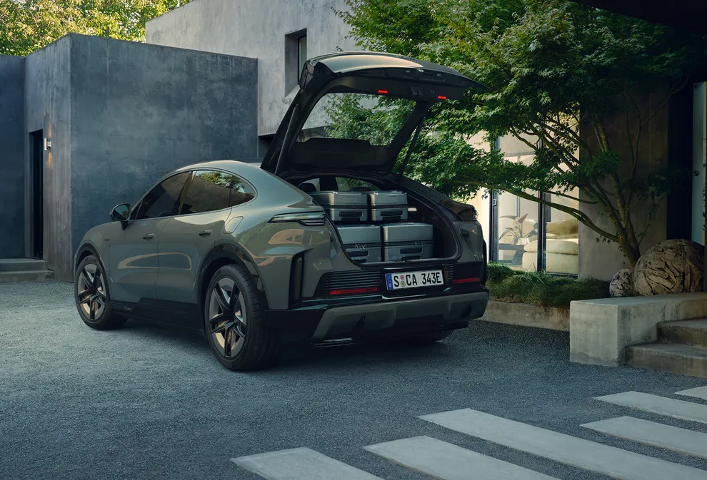 Blick von hinten auf ein Porsche Cayenne Turbo Coupé mit geöffnetem Kofferraum voller Koffern.