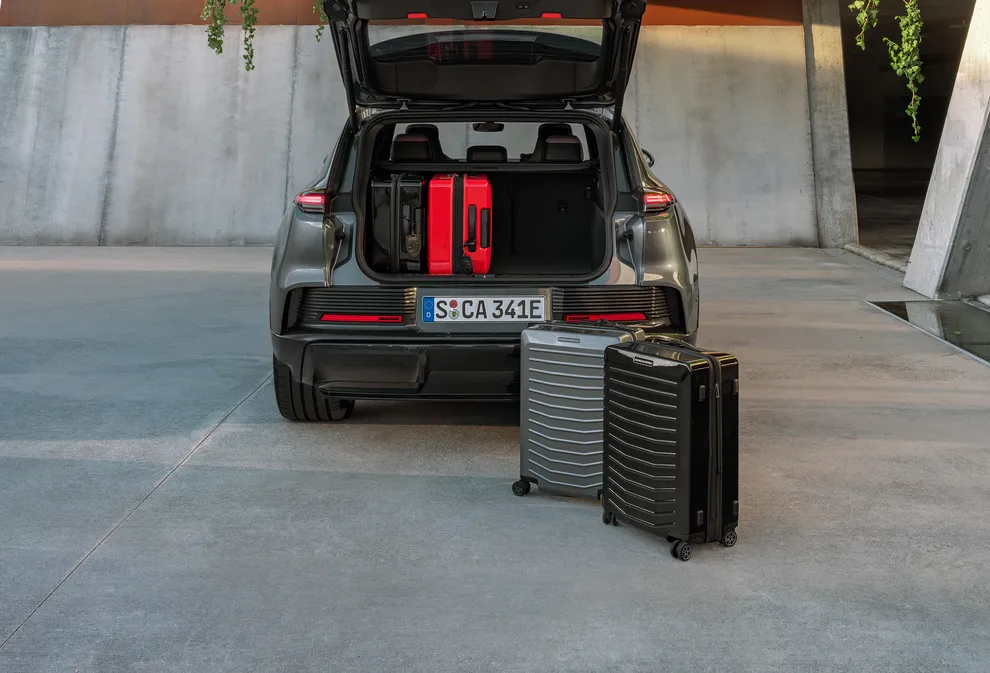 Ein Porsche Cayenne steht neben Koffern.