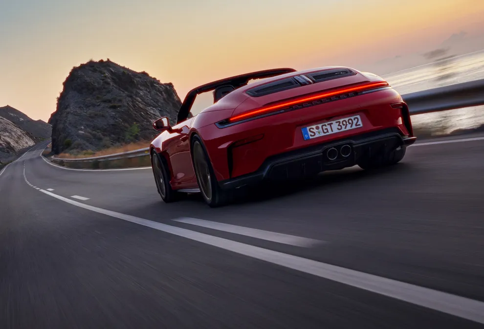 Rear view of a Porsche 911 GT3 S/C in Guards Red driving on a country road.