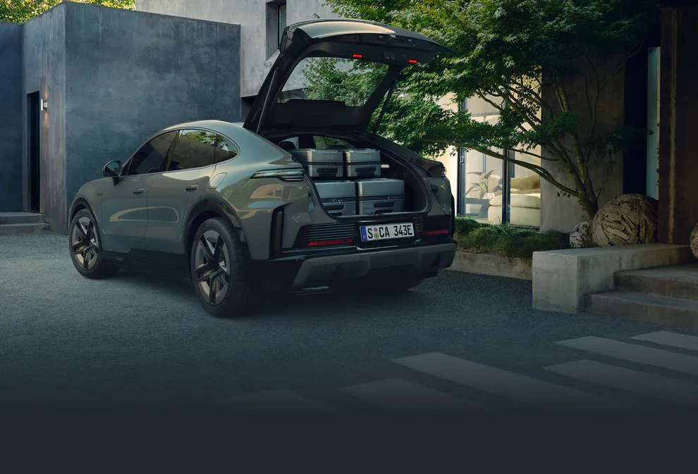 A Porsche Cayenne S Coupé Electric parked next to suitcases.