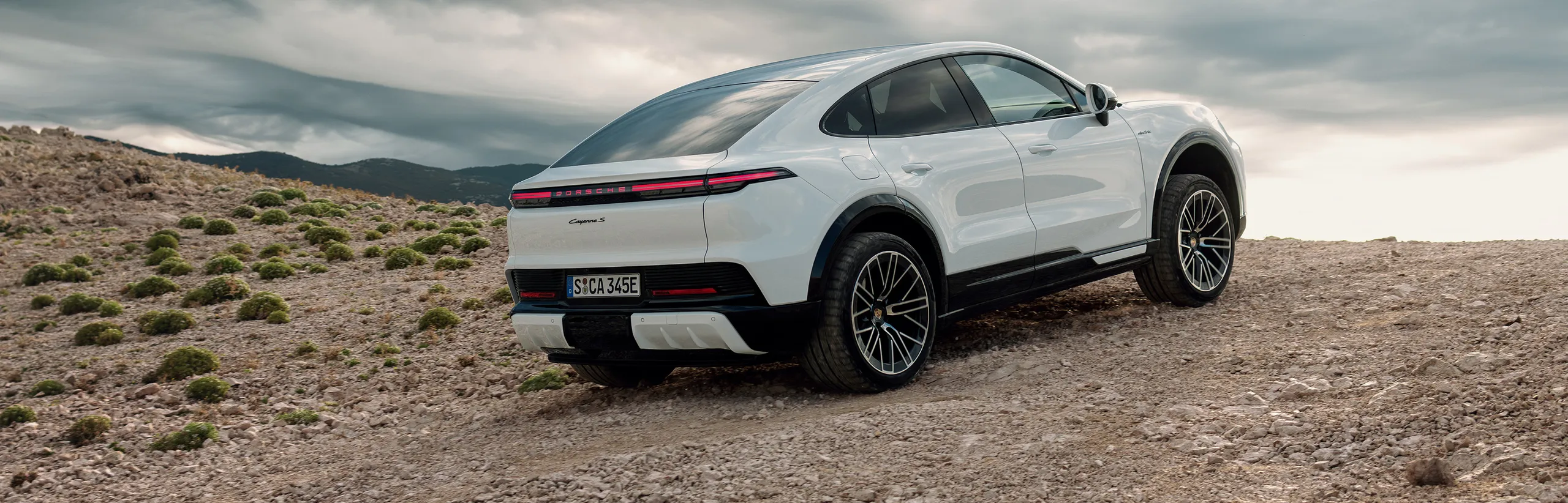 View of the front and side of a Porsche Cayenne S Coupé Electric in Carrara White Metallic.