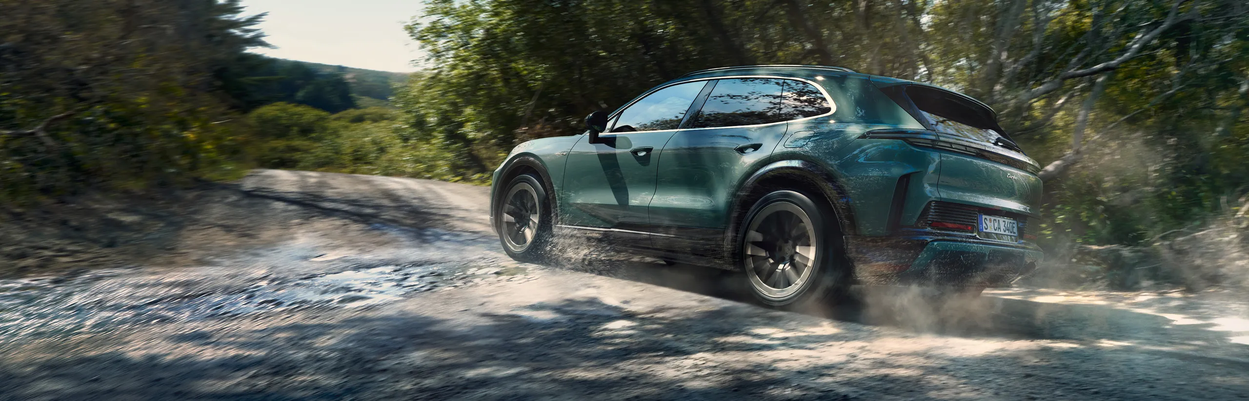 A Porsche Cayenne Turbo in Mystic Green Metallic driving on a country road. Side view.