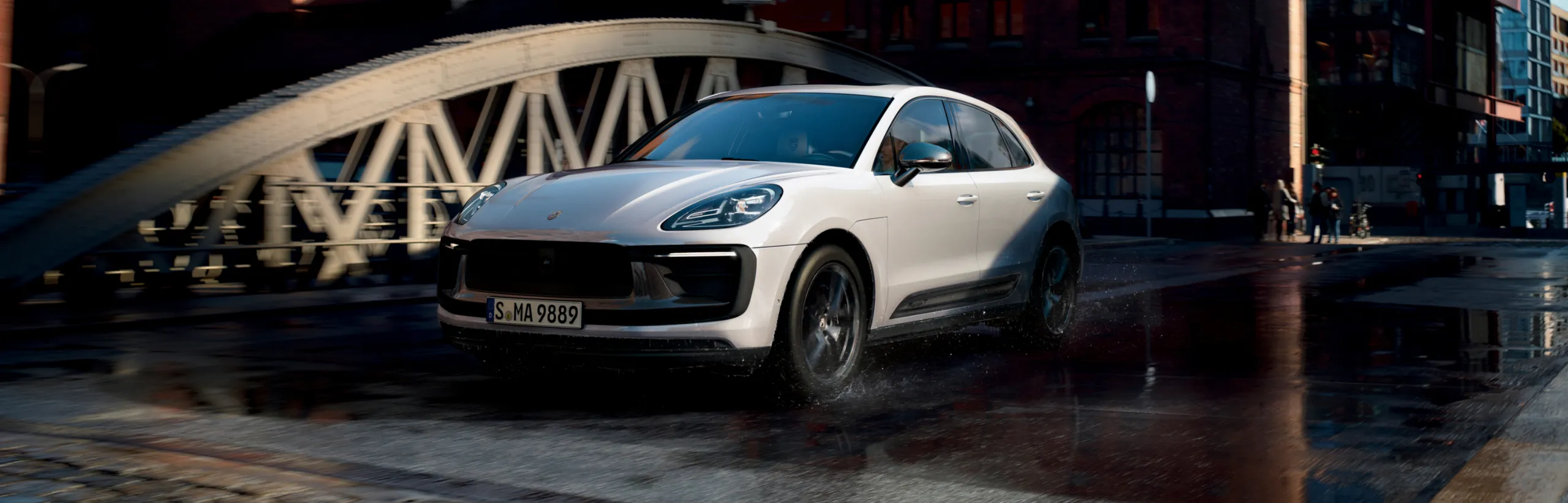 Porsche Macan T in White driving over a bridge in a city. Front and side views.