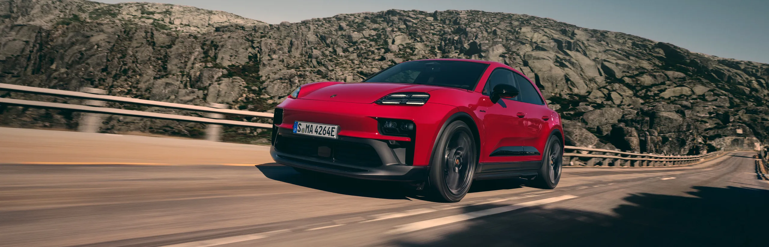 Scatto dinamico di una Macan GTS in Rosso Carminio, ripresa frontalmente e lateralmente.