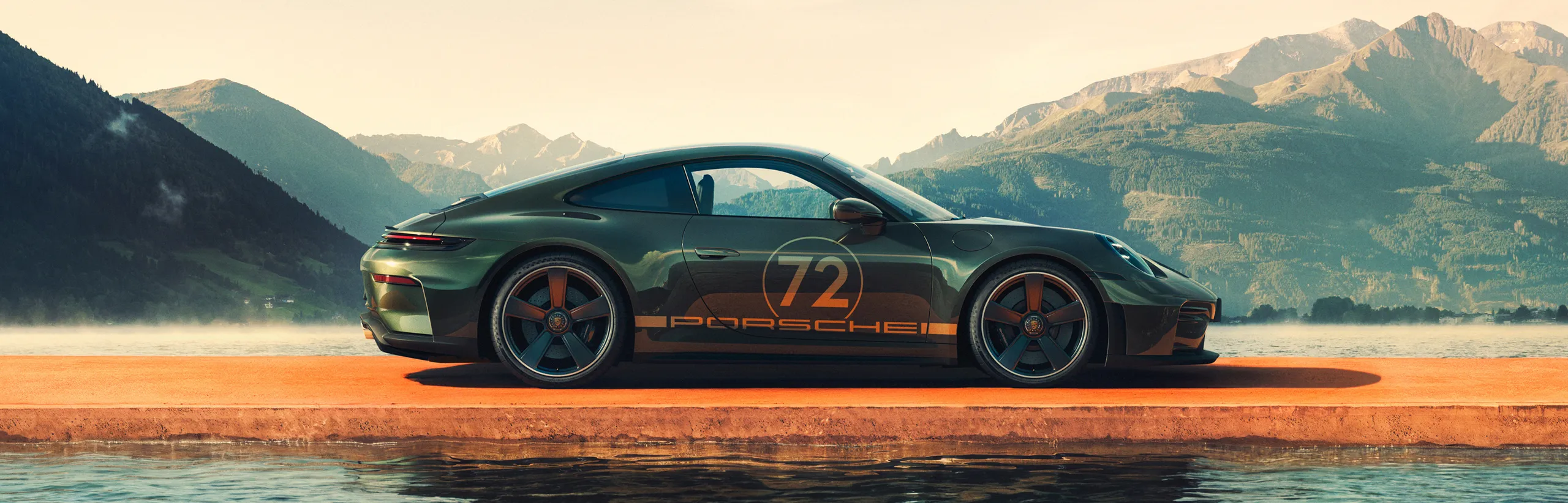 Side view of a Porsche 911 GT3 90 F. A. in F. A. Greenmetallic on a jetty. Mountains and a lake can be seen in the background.