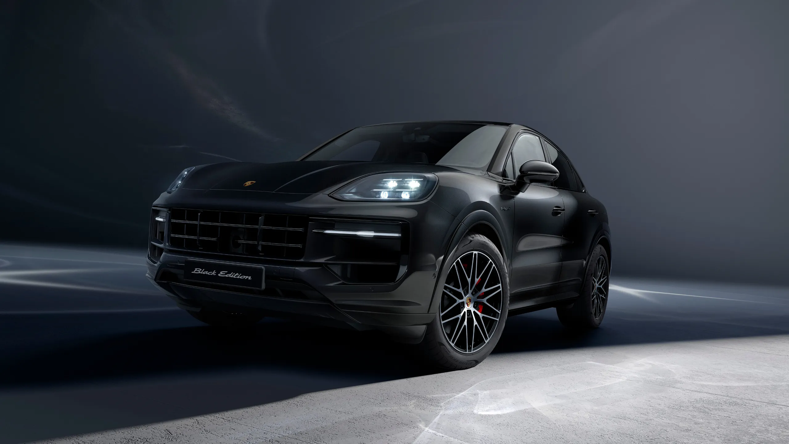View from the front showing the front and side of the Porsche Cayenne Black Edition in Chromite Black Metallic.
