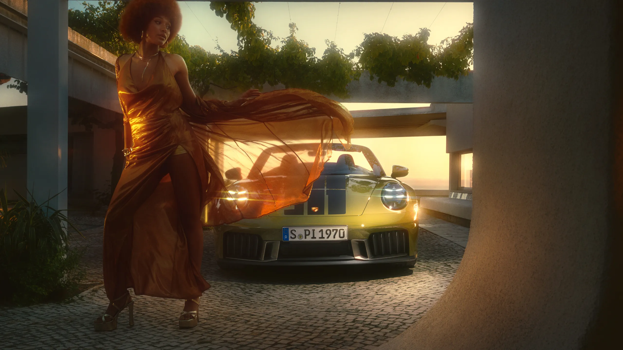Frontansicht des Porsche 911 Spirit 70 in der Lackierung Olive Neo. Im Vordergrund tanzt eine Frau in langem Kleid.