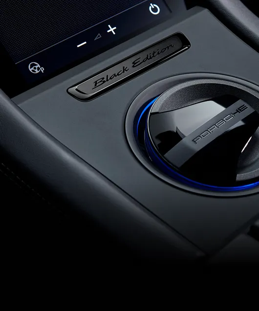 Detaljert visning av merket på midtkonsollen i Porsche Taycan 4S Black Edition.