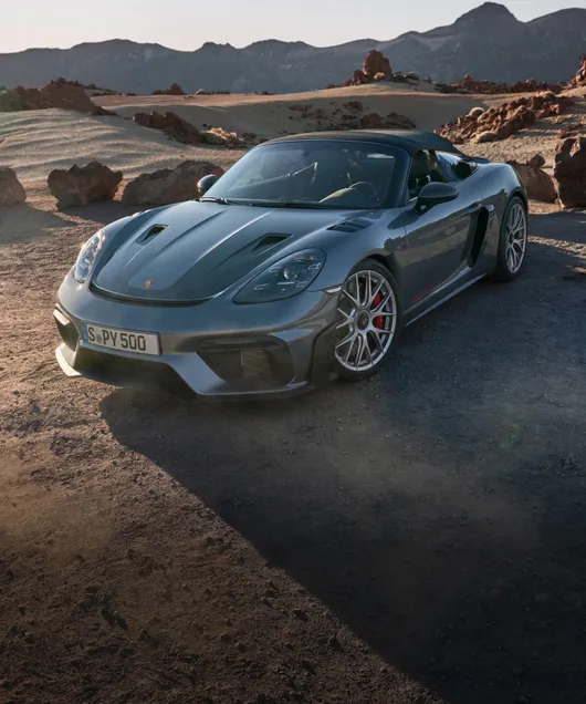 Een blik op de voorkant en zijkant van de Porsche 718 Spyder RS in Vanadiumgrijs metallic van iets verder af.