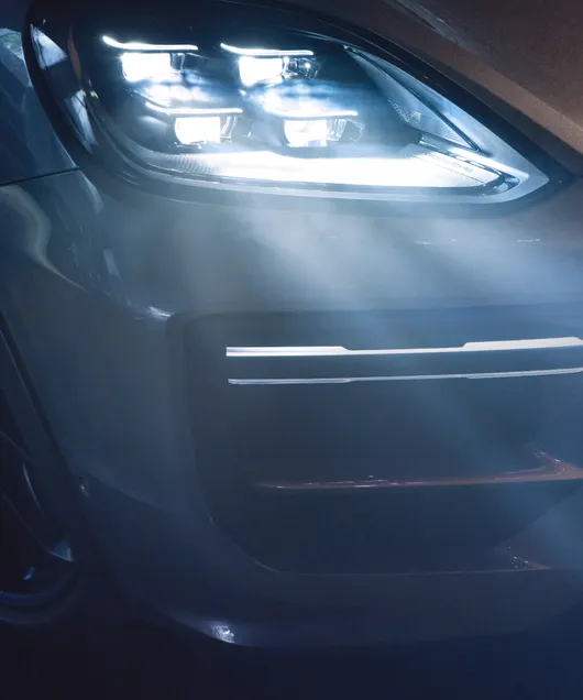 Porsche Cayenne Turbo E-Hybrid Coupé avec pack GT en Gris Quartzite métallisé. Vue détaillée des phares matriciels HD à LED.