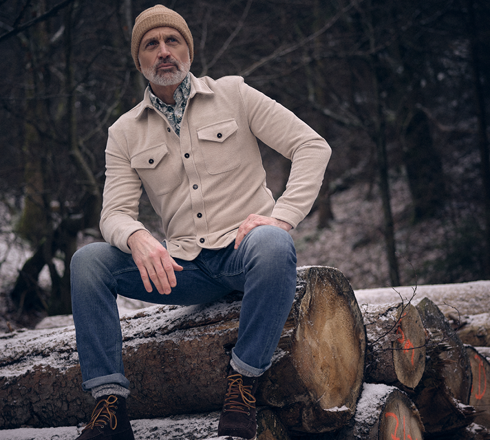 Man gekleed in een beige overshirt en een spijkerbroek