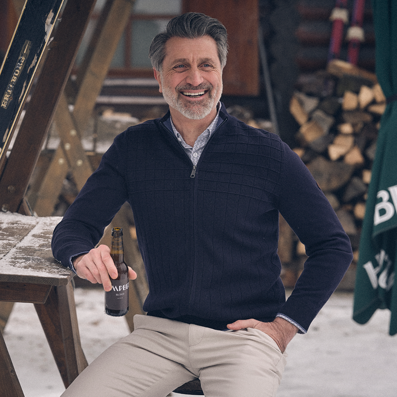 Man gekleed in donkerblauw vest en beige broek