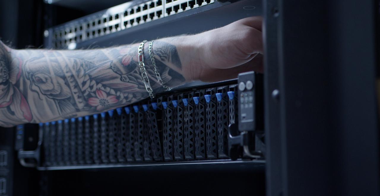 Technician reaching into a dc2scale server rack , with a boosteroid GPU Asus server with blue tabs