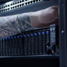 Technician reaching into a dc2scale server rack , with a boosteroid GPU Asus server with blue tabs