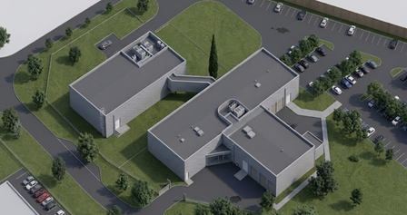 Aerial view of modern rectangular Datacenter in Castres, south of France, with flat roofs, surrounded by green lawns and parking lots with several cars and trees.