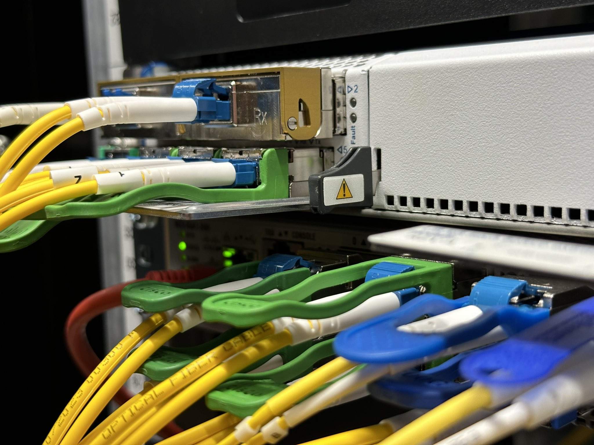Close-up of networking equipment with various colored cables connected to ports, featuring green, yellow, and blue connectors. DWDM transport in DC2SCALE PAR3 Paris-Vélizy.