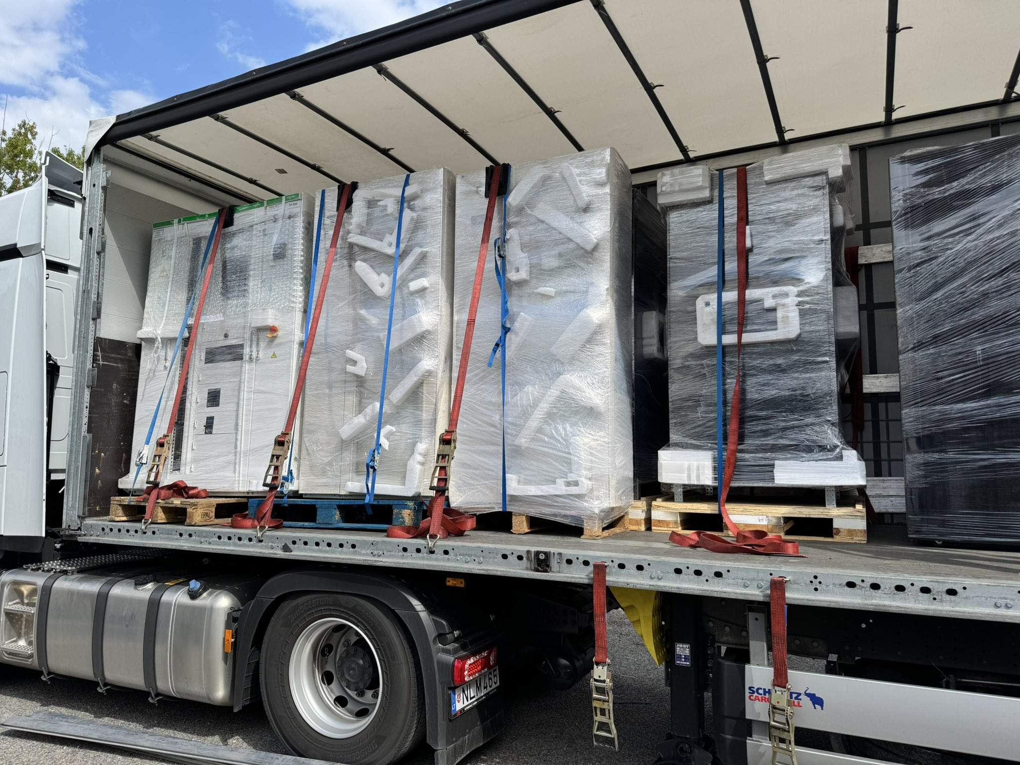 Secure loading of racks and data center equipment onto a truck, with plastic packaging and securing straps, ready for transport to site