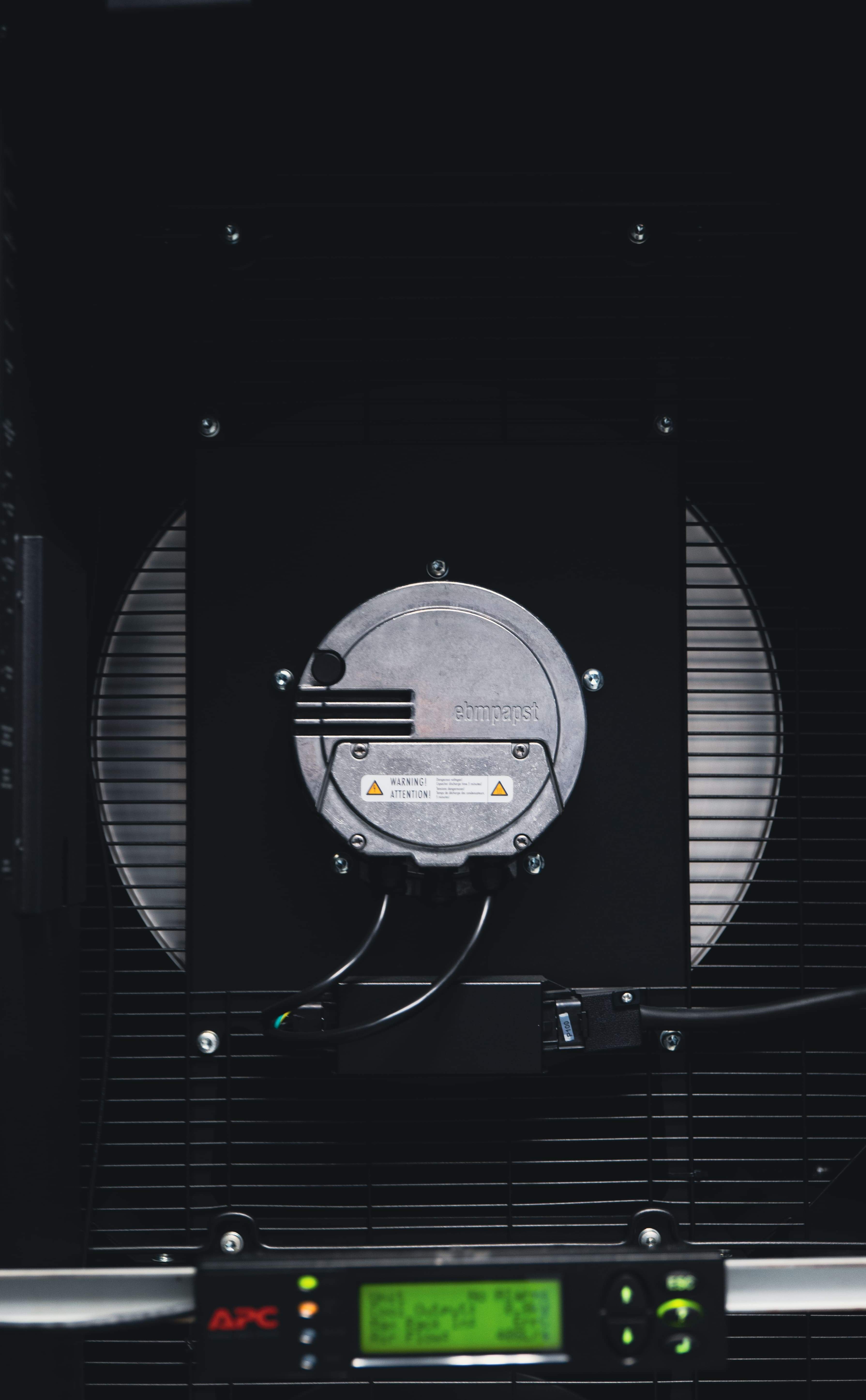 Close-up of industrial equipment (Schneider Inrow) with a circular component and attached cables, set against a dark background with a digital display at the bottom.