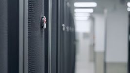 A close-up of a secure lock on an APC by Schneider server rack in the brightly lit aisle of the dc2scale PAR3 data center