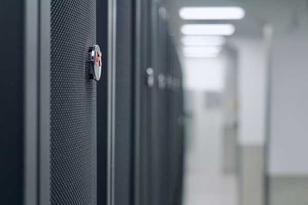 A close-up of a secure lock on an APC by Schneider server rack in the brightly lit aisle of the dc2scale PAR3 data center