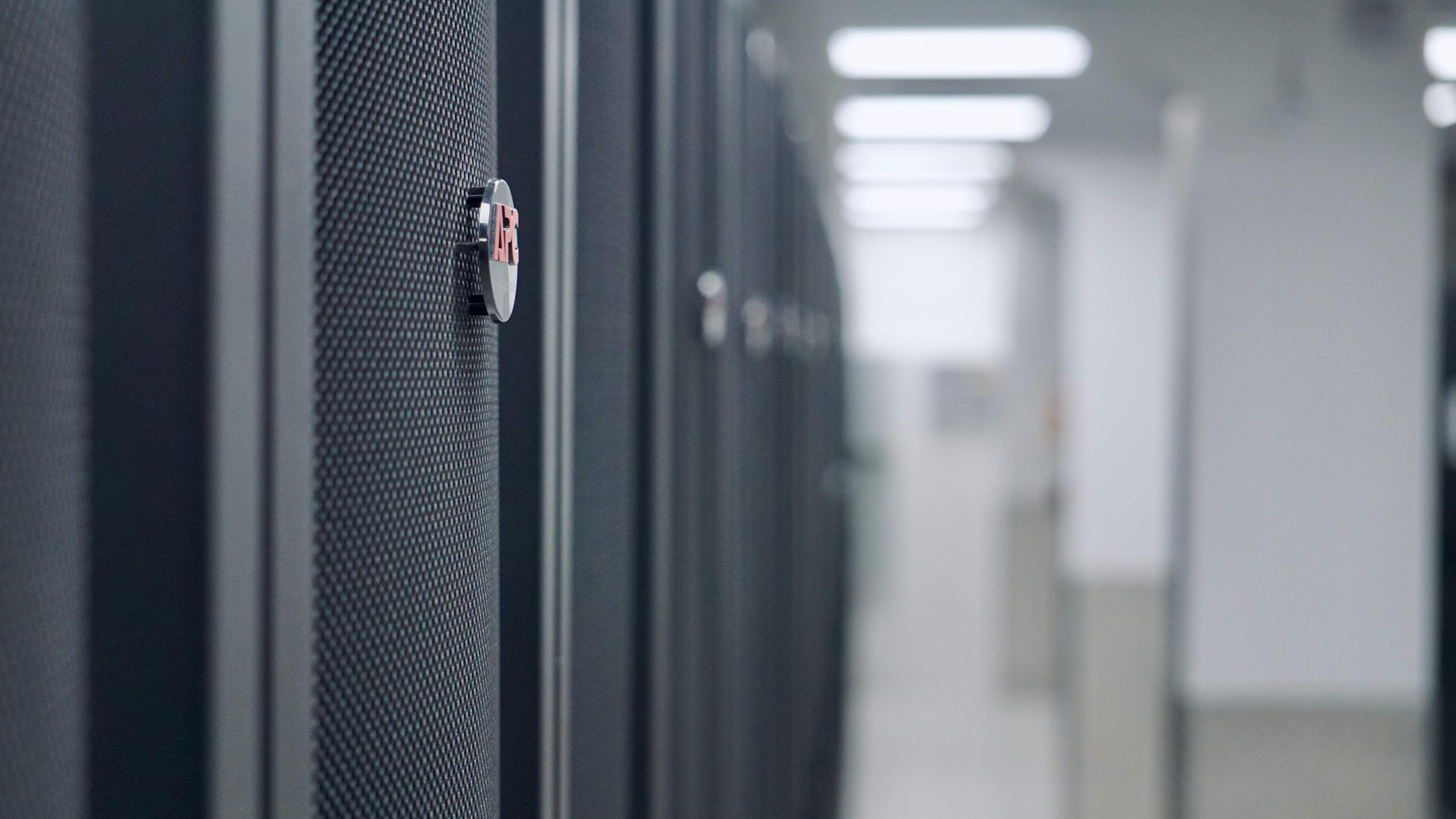 A close-up of a secure lock on an APC by Schneider server rack in the brightly lit aisle of the dc2scale PAR3 data center