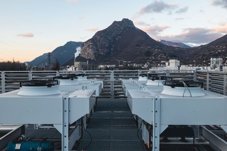 Rooftop HVAC units with mountain backdrop at sunset, framed by industrial buildings and a clear sky with scattered clouds.