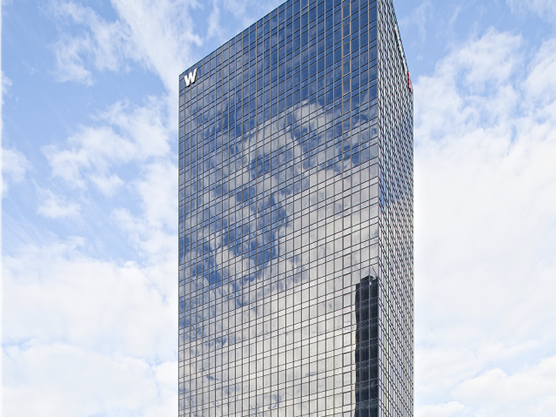 Vue extérieure de la Tour W, immeuble de bureaux emblématique à La Défense, avec sa façade vitrée réfléchissant le ciel, offrant un espace de travail moderne et lumineux au cœur du quartier d'affaires.
