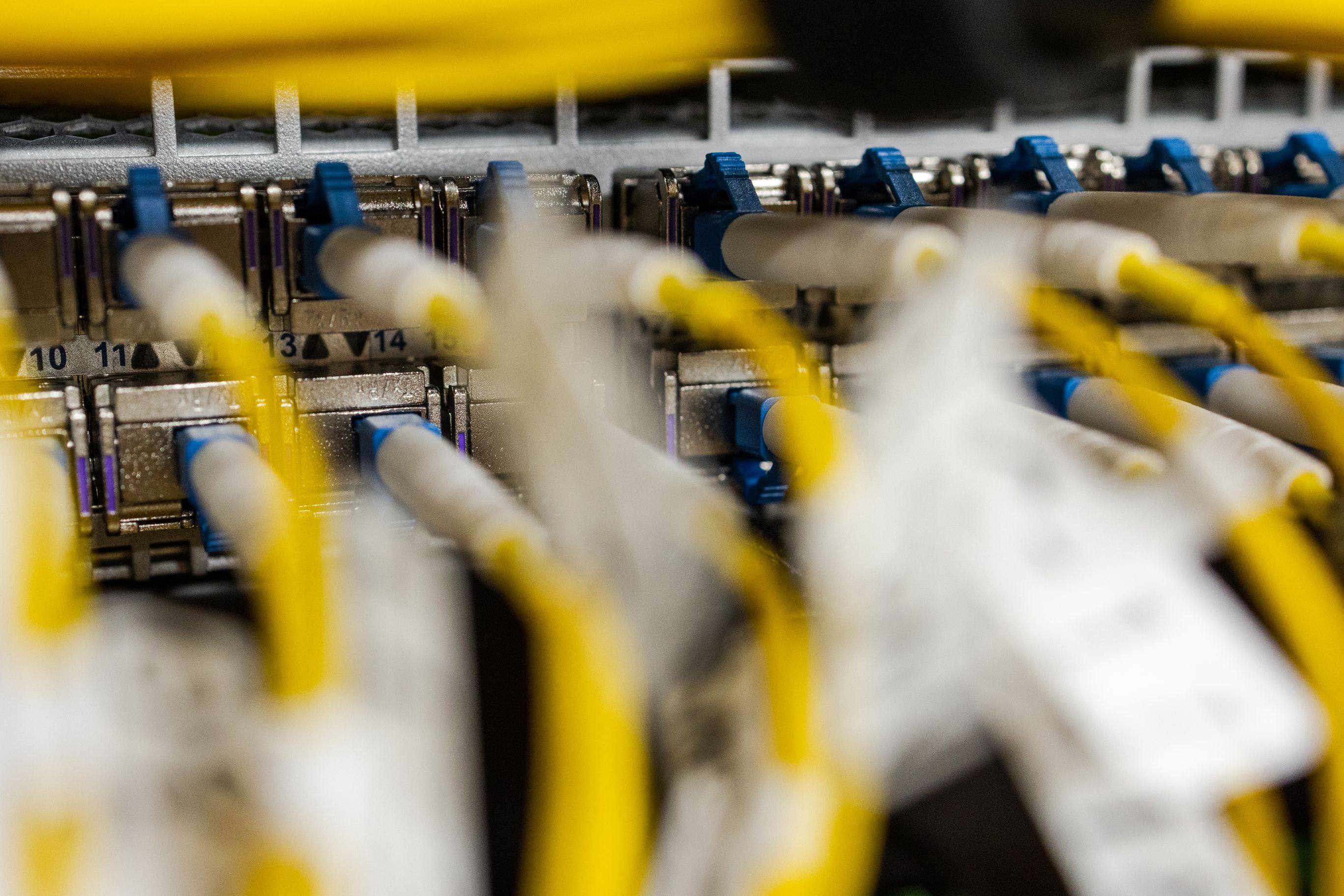 Zoom on yellow fiber cables connected to a switch in rack dc2scale par2 velizy