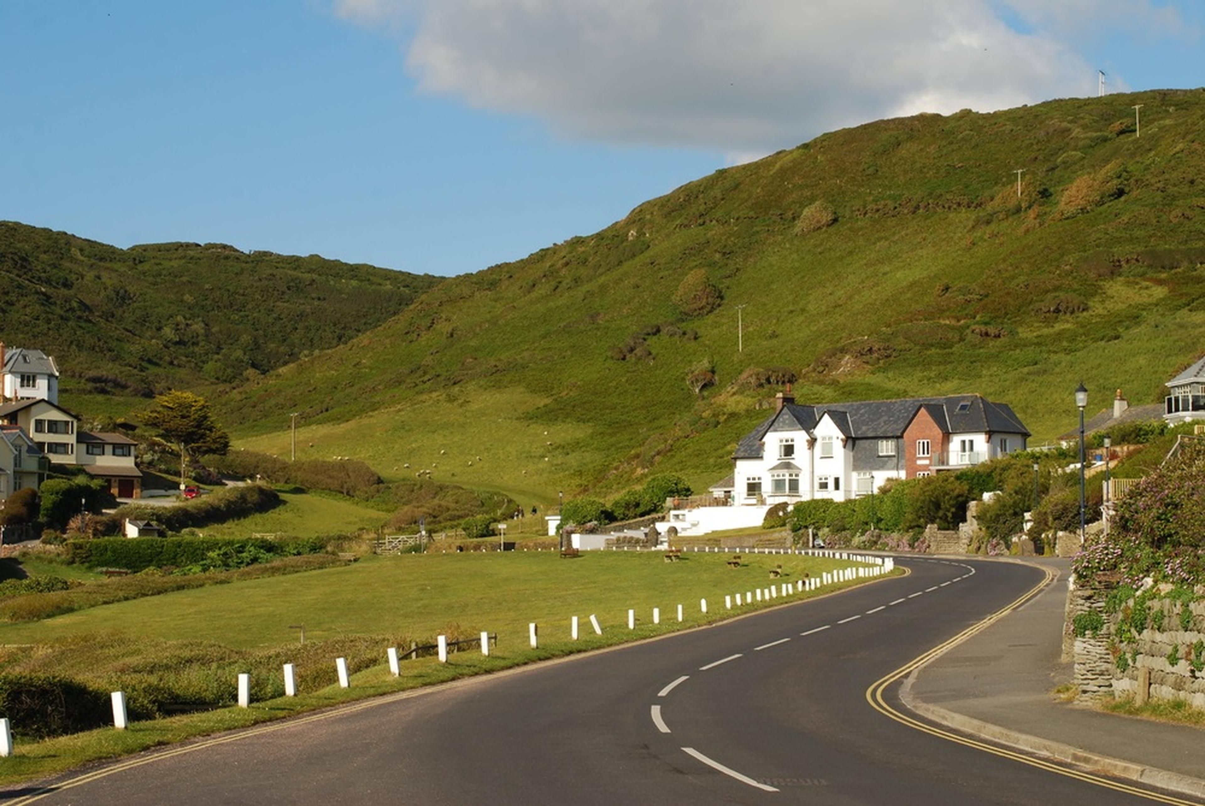 Winding road through a lush green hillside with quaint houses