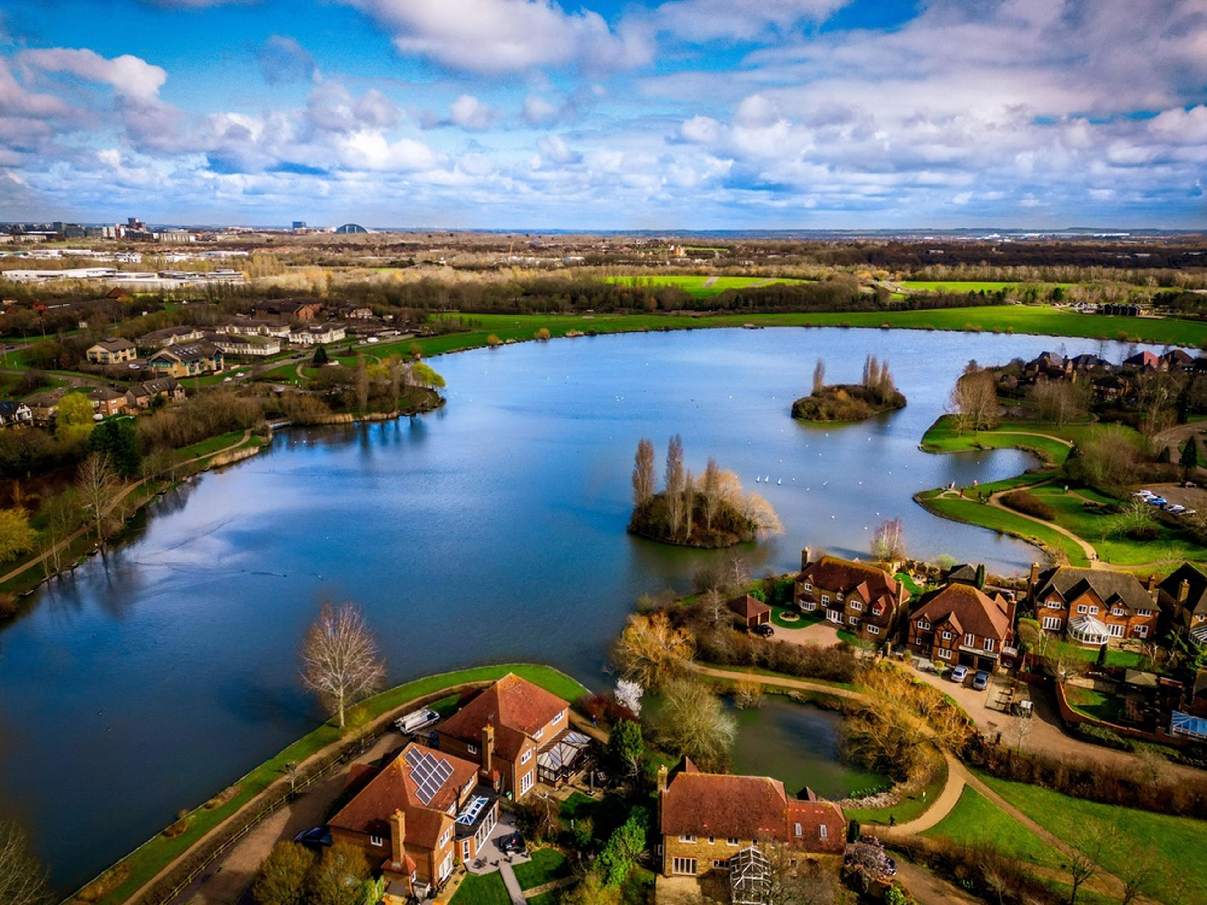 Aerial view of a scenic lake with small islands, surrounded by houses