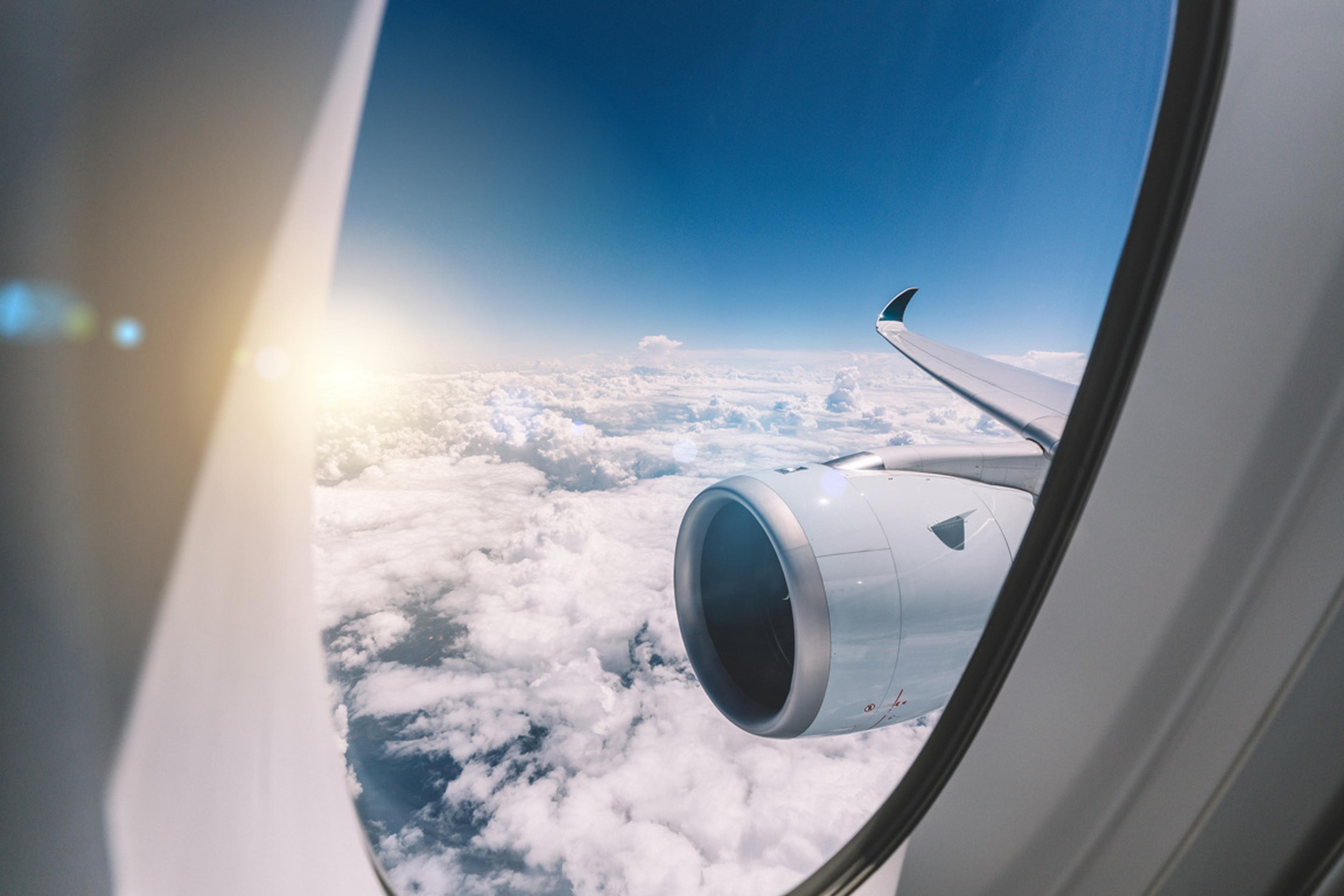 Image looking out an airplane window with sunny skies.