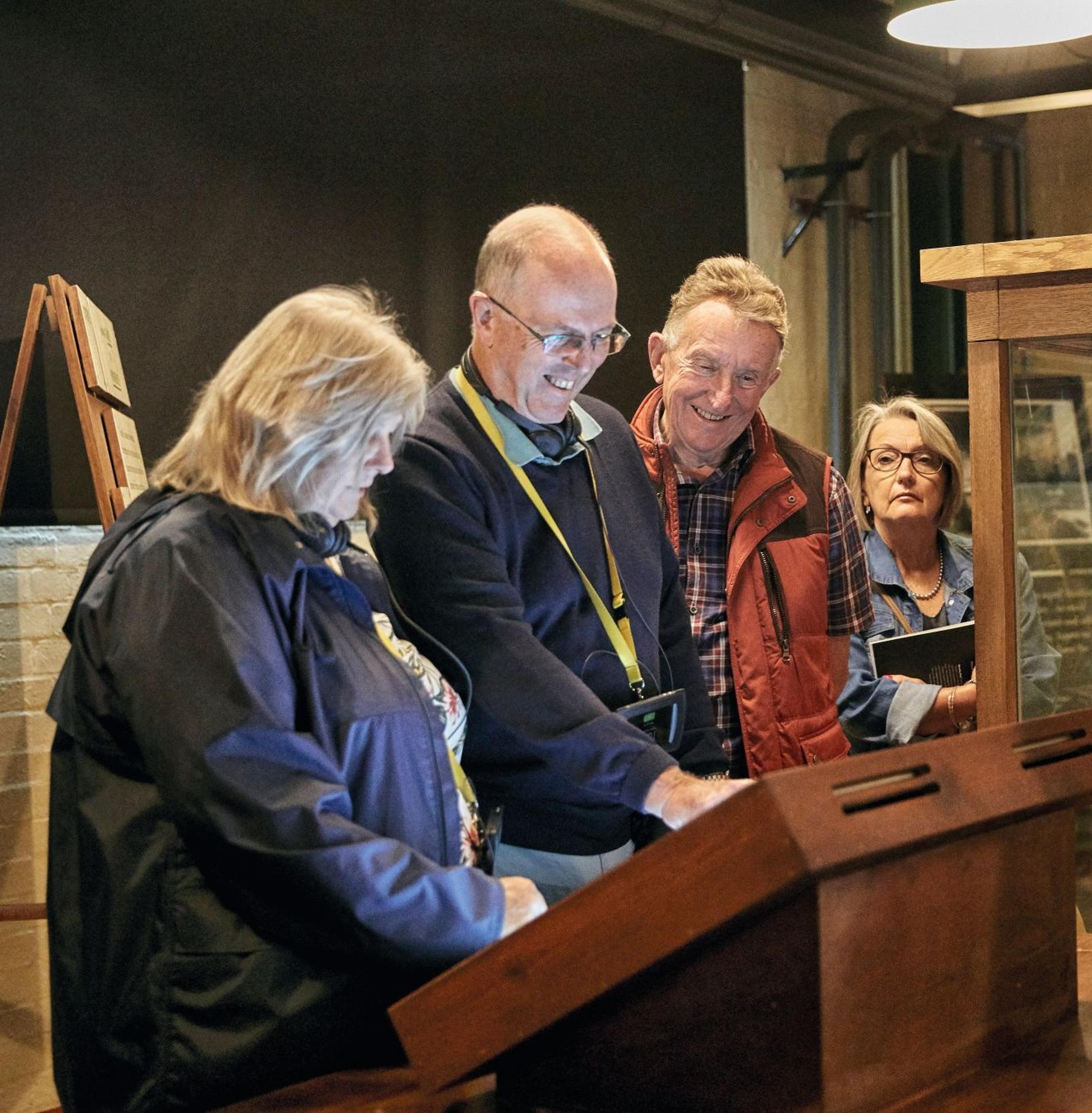 Four people gather around an interactive display in a dimly lit room, looking engaged and smiling.